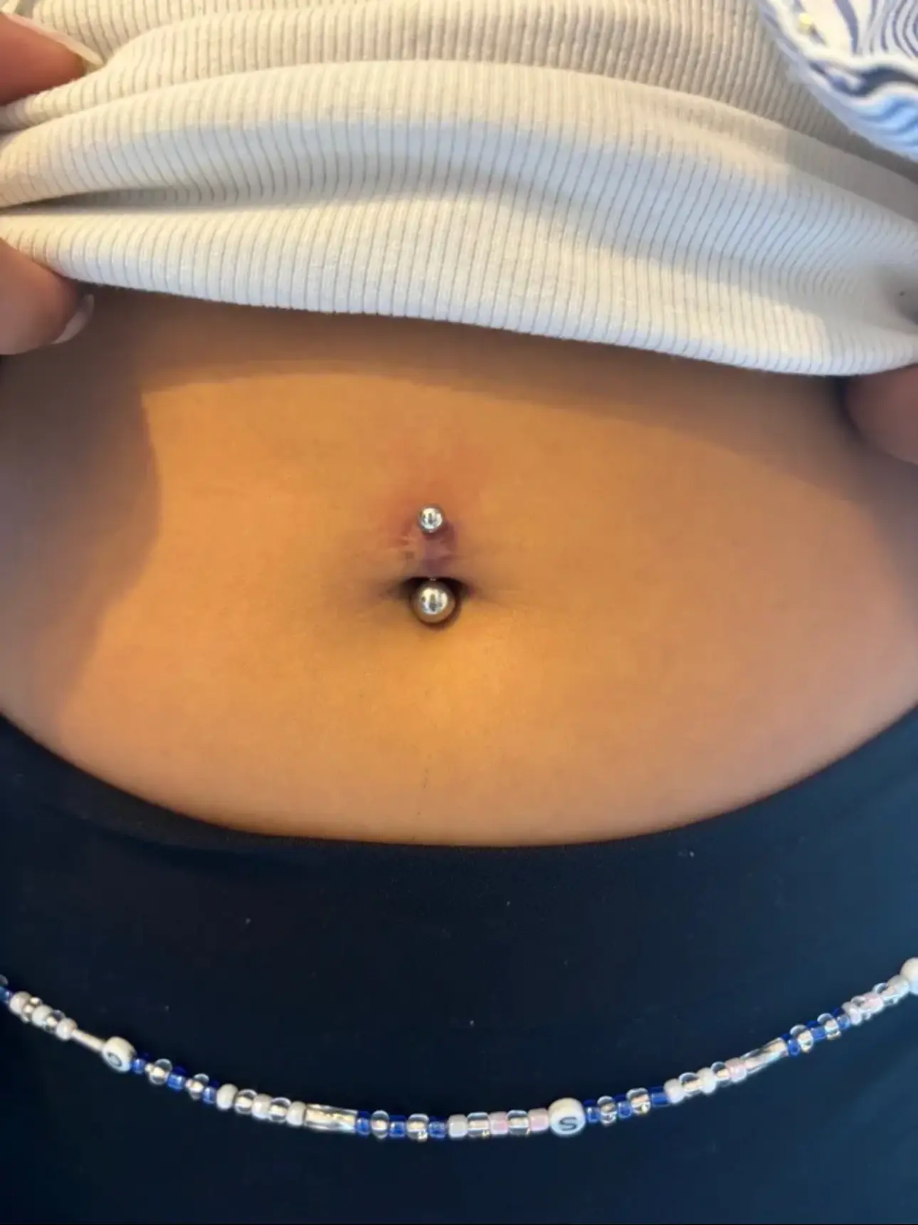 Silver curved barbell navel piercing